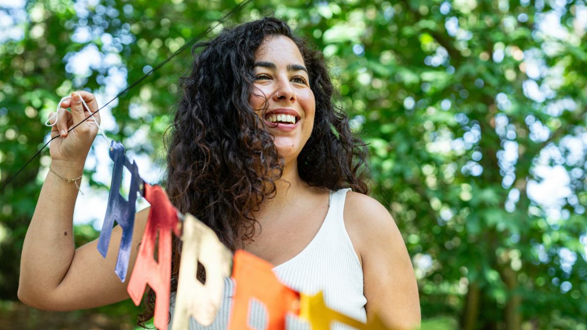 A woman in her 30s at a birthday party, hanging a sign