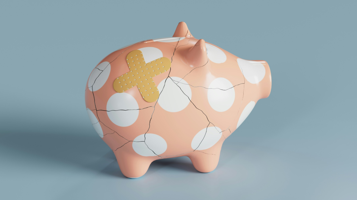 A picture of a dotted piggy bank that's been glued back together and has a plaster on it
