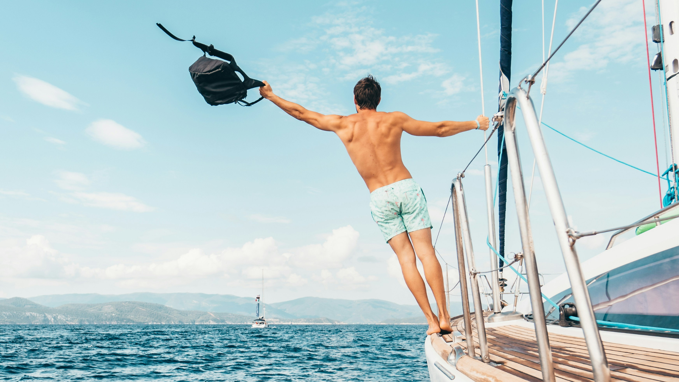 A man leans off the side of a boat, looking happy