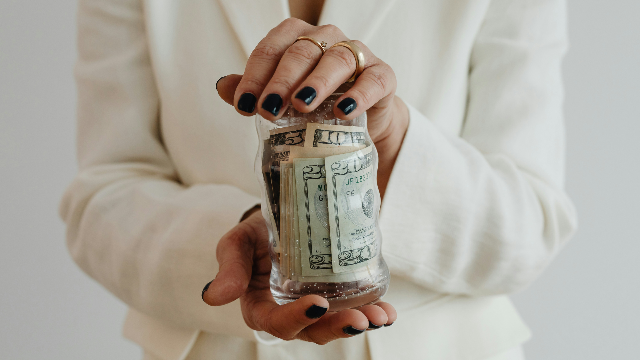 A woman holds a glass jar filled with notes