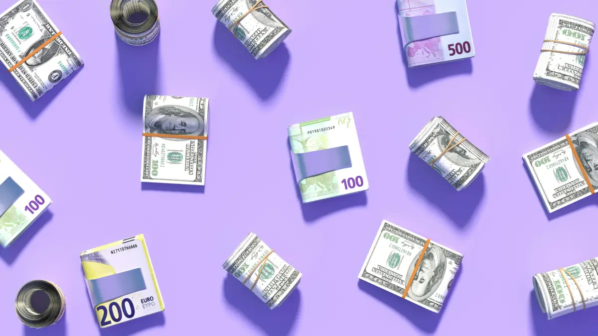 Piles of different currency money notes sit against a stylised purple background