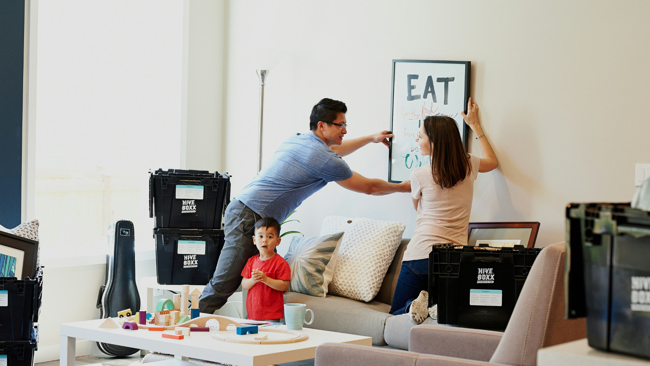 A young family hang a picture in their new home