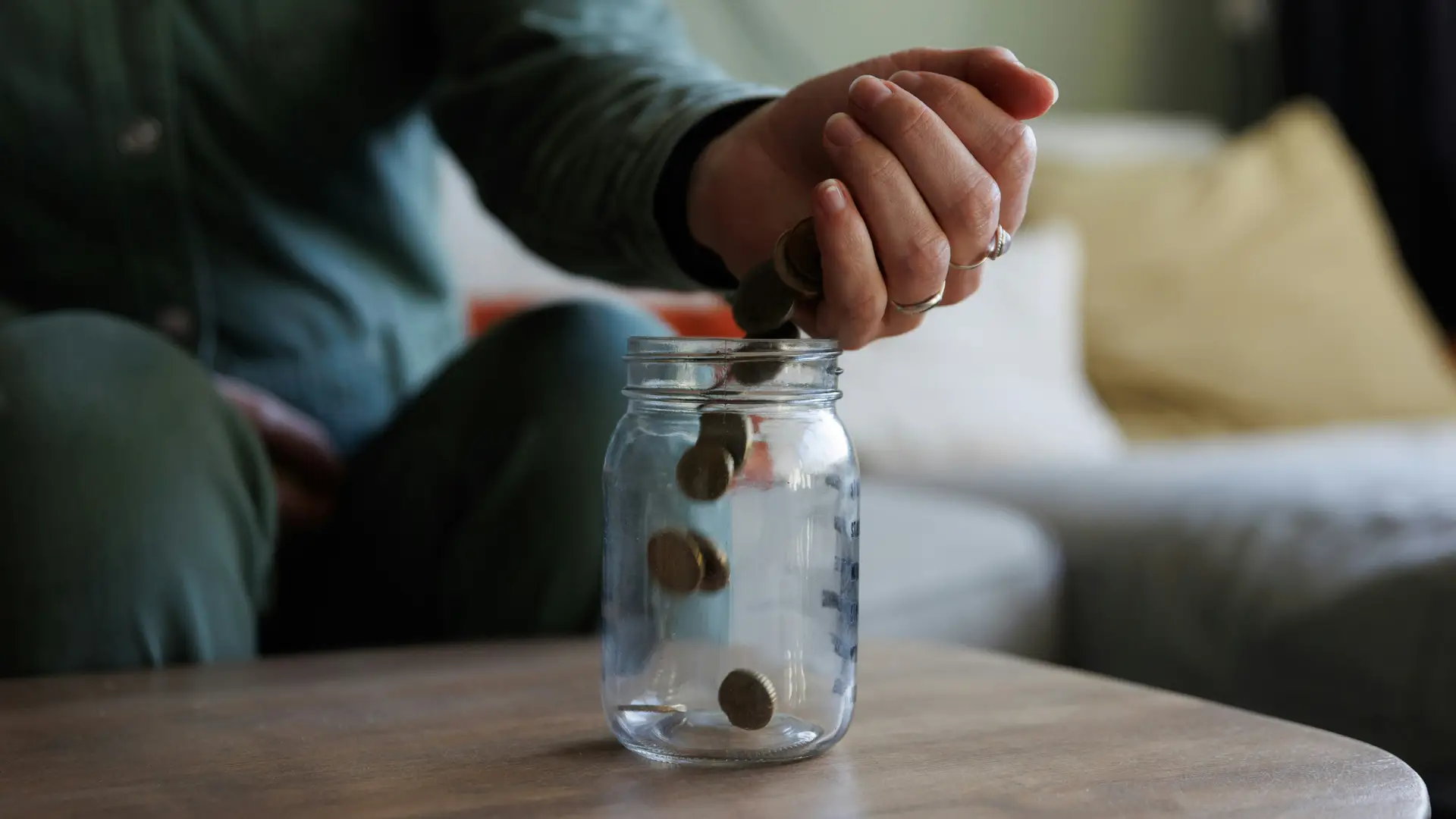 Someone pours coins into a savings jar
