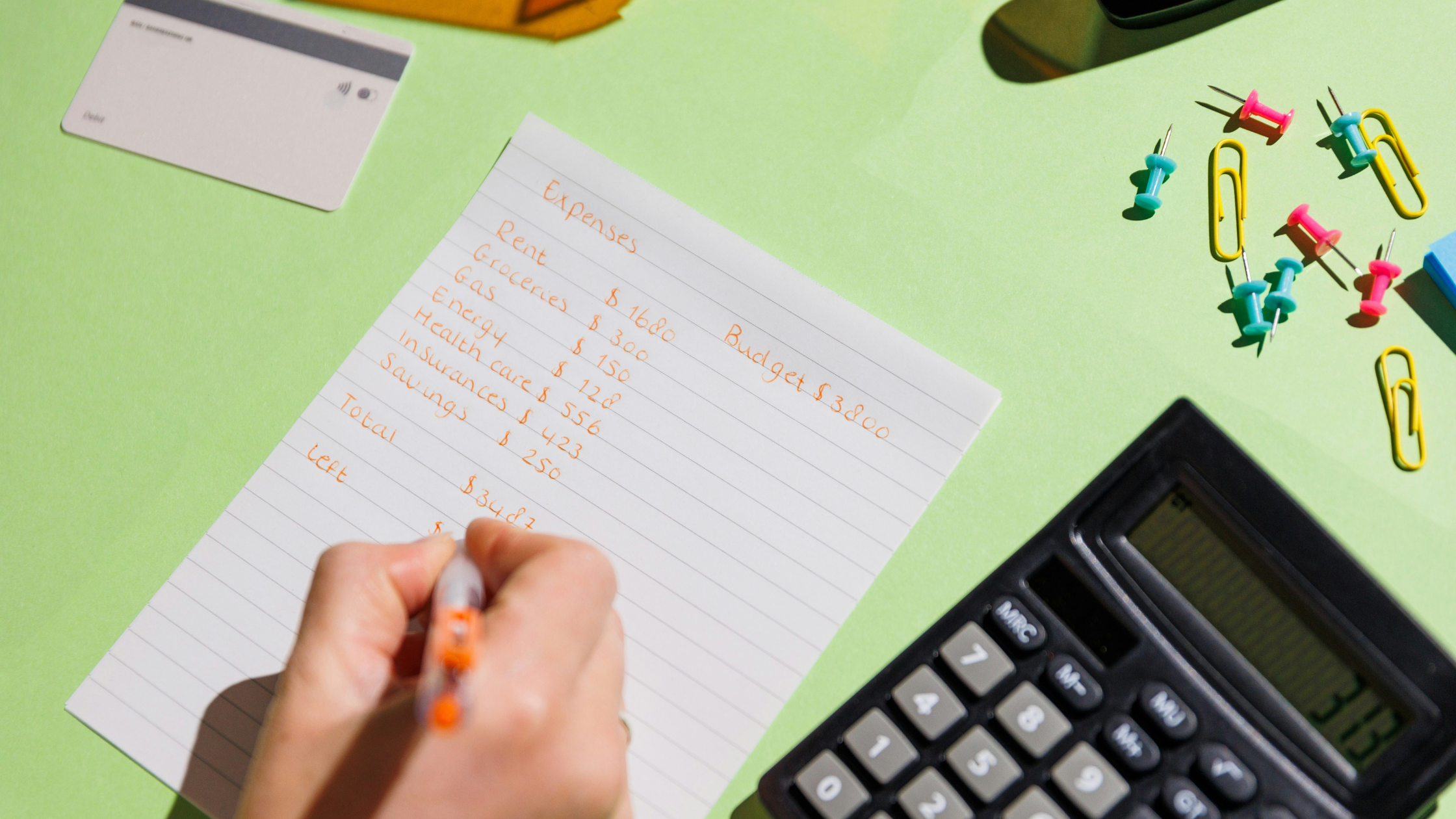 Someone writes down a list of expenses to work out their budget