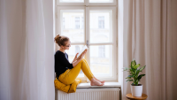 A young woman reading by a bright woman
