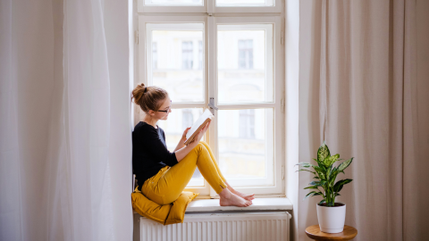 A young woman reading by a bright woman