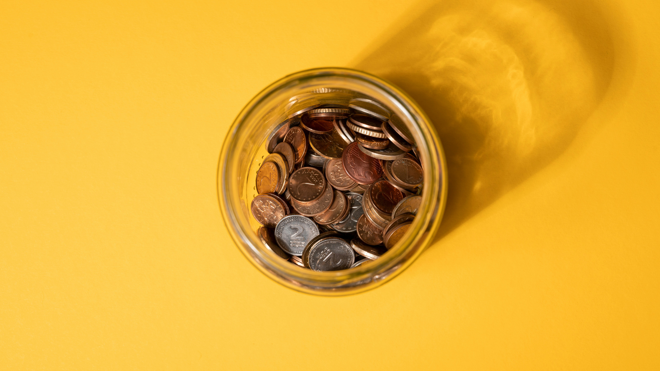 A glass savings jar with coins inside