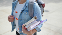 A picture of a student holding a pile of books