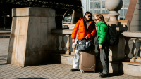 two young women talk outside a train station