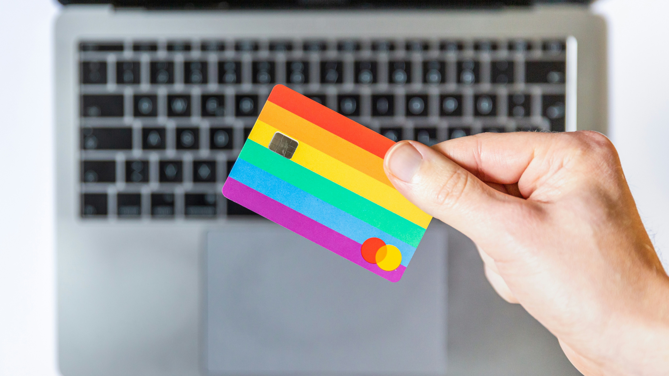 a hand holding a colourful, striped bank card