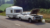 a vintage car that's attached to a caravan has broken down