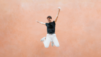 a man jumps up against a pink background
