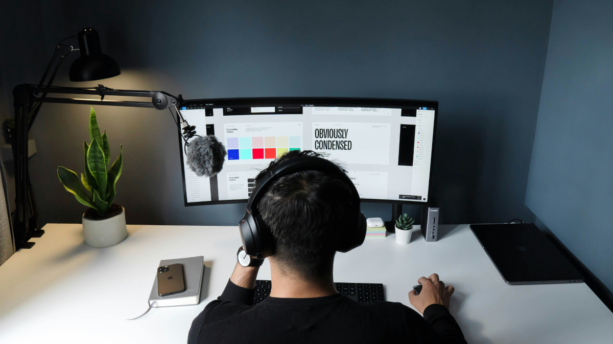 a man works at his wide-screened computer monitor