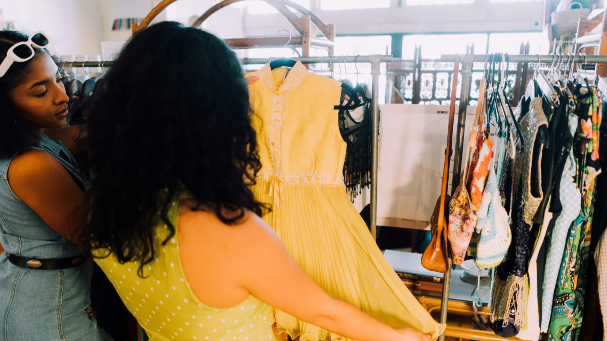 two woman look at a yellow dress in a clothes store