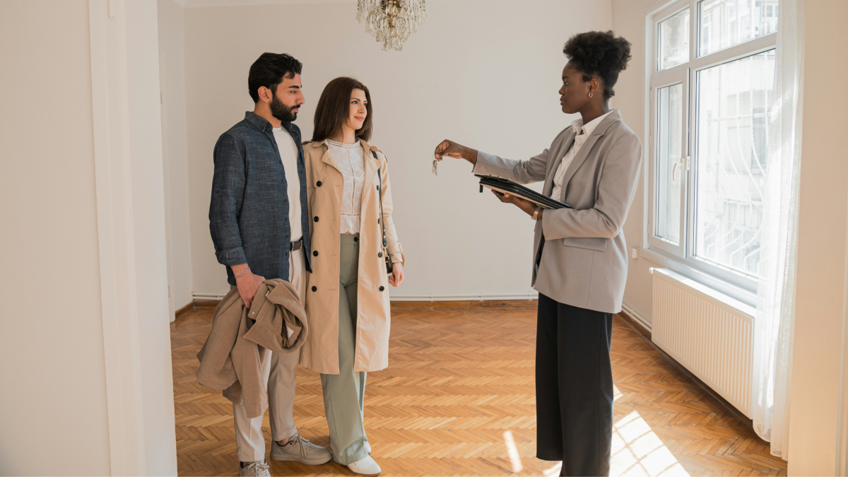 a woman shows a young couple around a new house