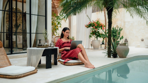 a stylish woman sits by a pool and works