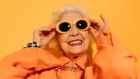 an elderly woman wears bright sunglasses and smiles
