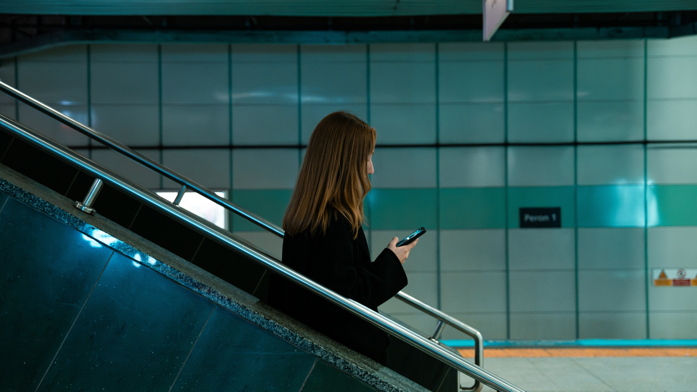 a woman texts on an escalator