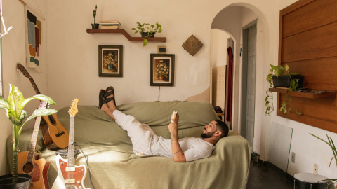 a man lies on his couch with his feet up and texts