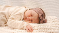 a baby lies asleep in her cot