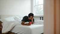 a man lies on his bed looking at his phone