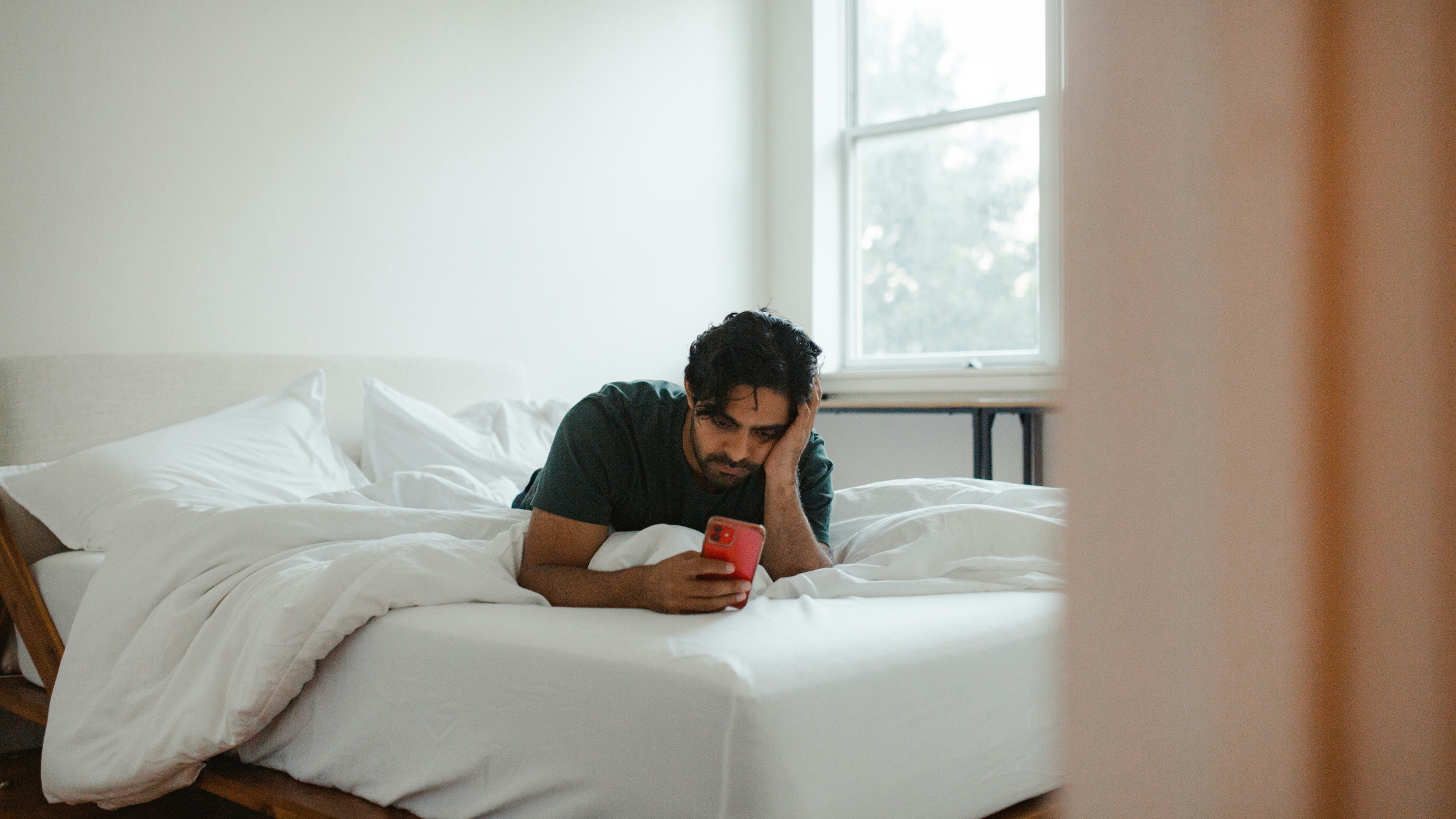 a man lies on his bed looking at his phone