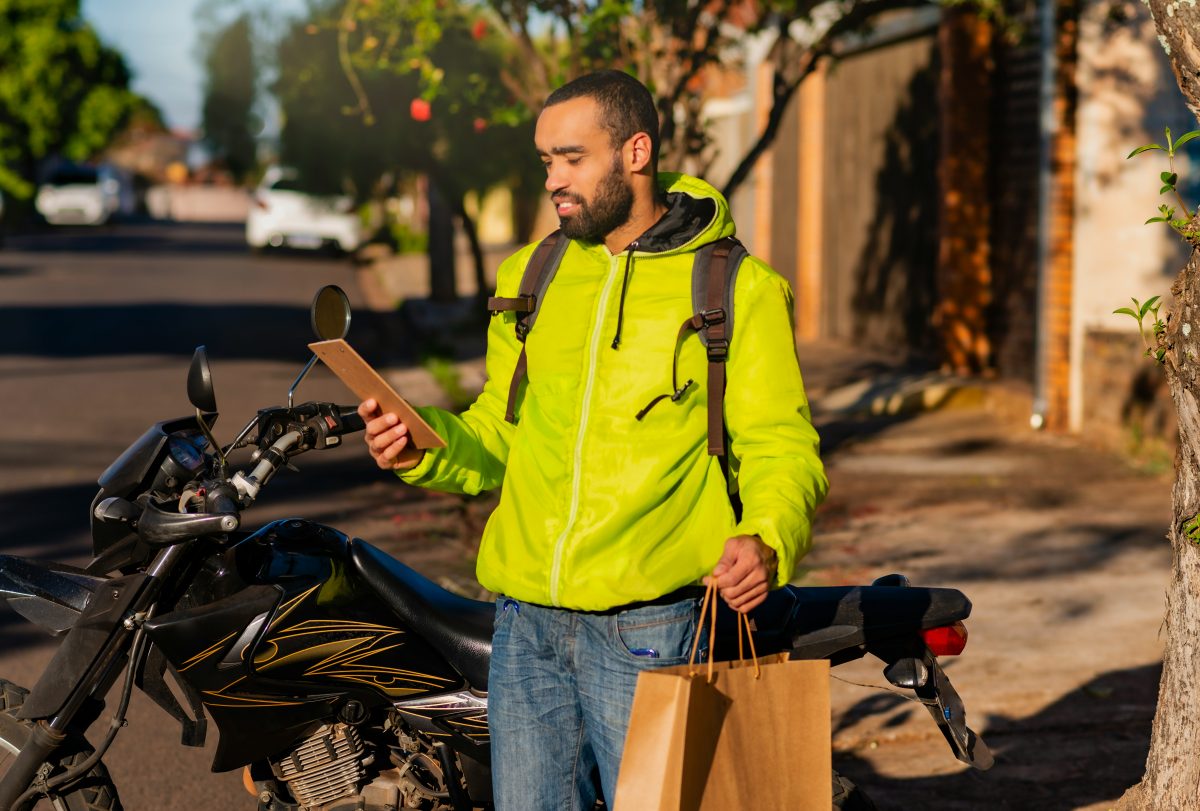 A smiling delivery driver looking at his phone