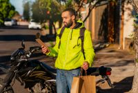 A smiling delivery driver looking at his phone