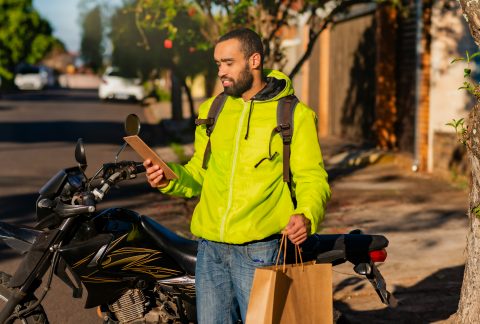 A smiling delivery driver looking at his phone