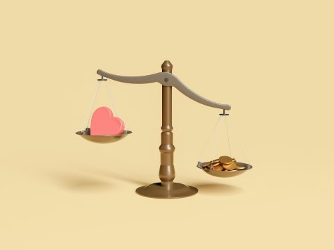 A set of scales with coins on one side and a heart on the other