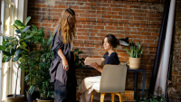 two women talk in a stylish office