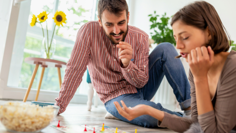 a woman and man play a boardgame on the floor