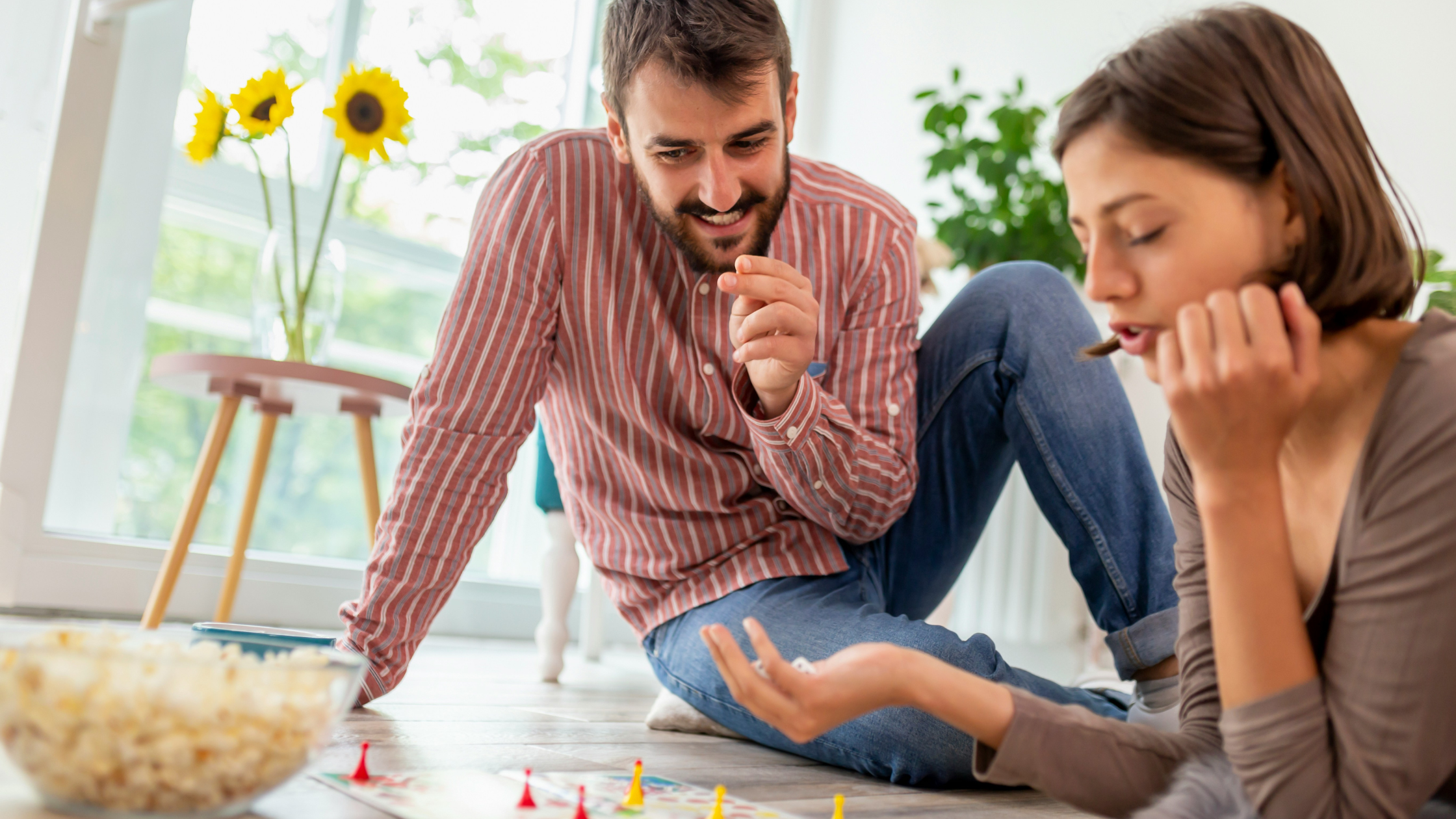 a woman and man play a boardgame on the floor