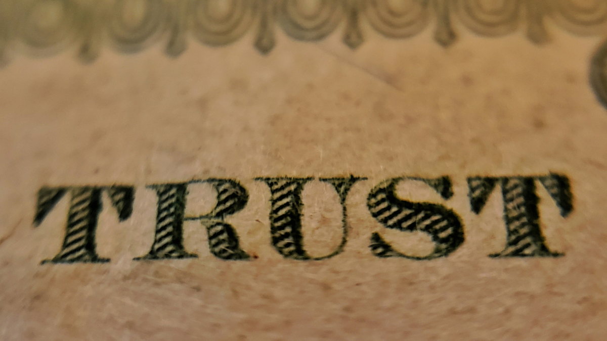 the word 'trust' on a banknote