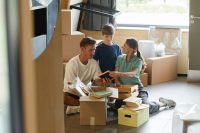 A young family sit surrounded by moving boxes