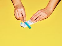Someone squeezing the last bit of toothpaste out of a toothpaste tube.
